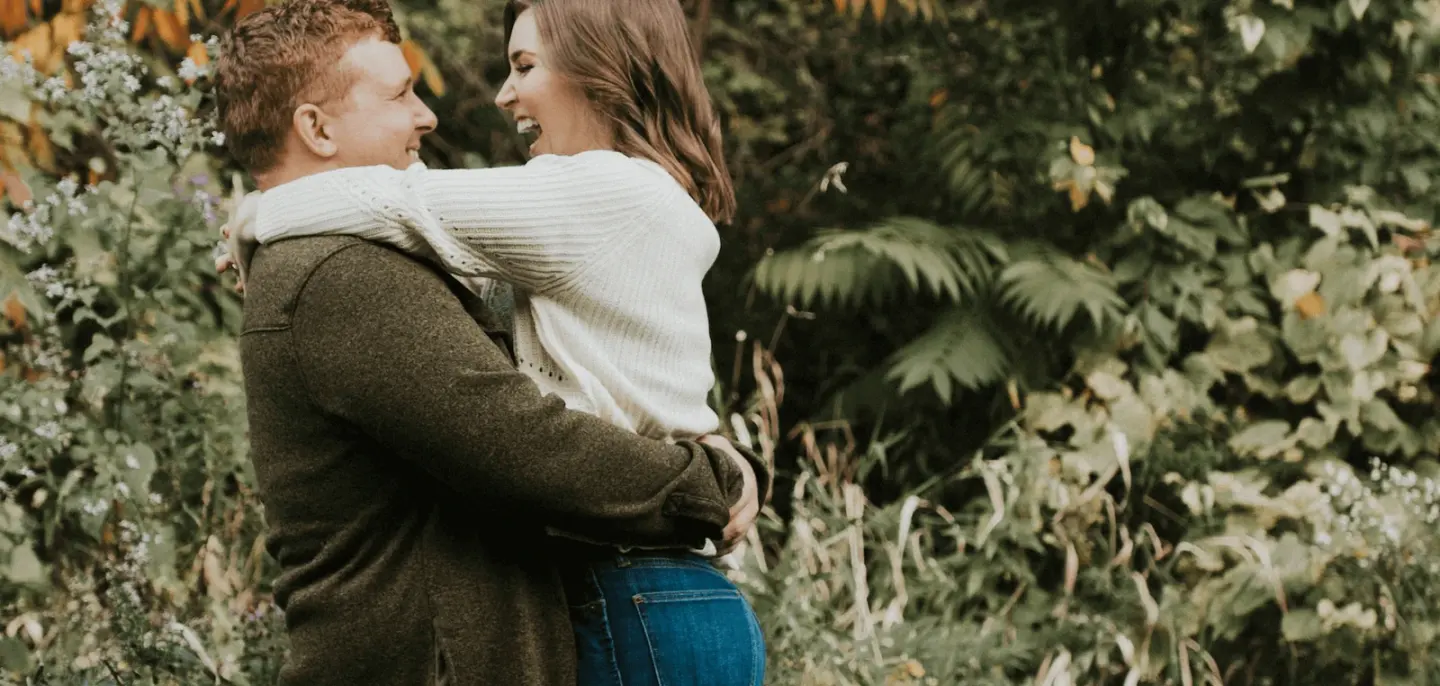 An engaged couple holding hands among trees